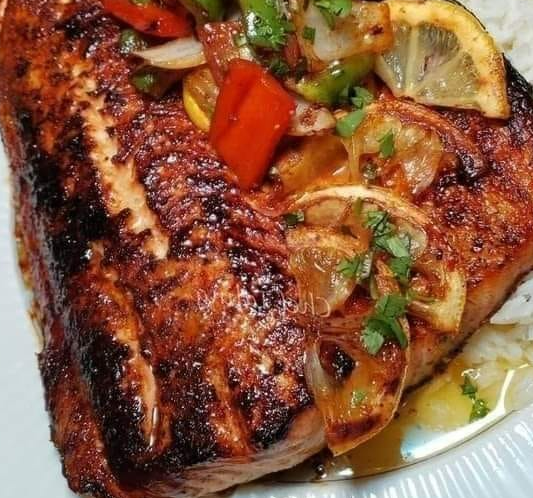 Grilled Jerk Lemon Pepper Salmon with sautéed bell peppers and lemon slices on a plate with rice