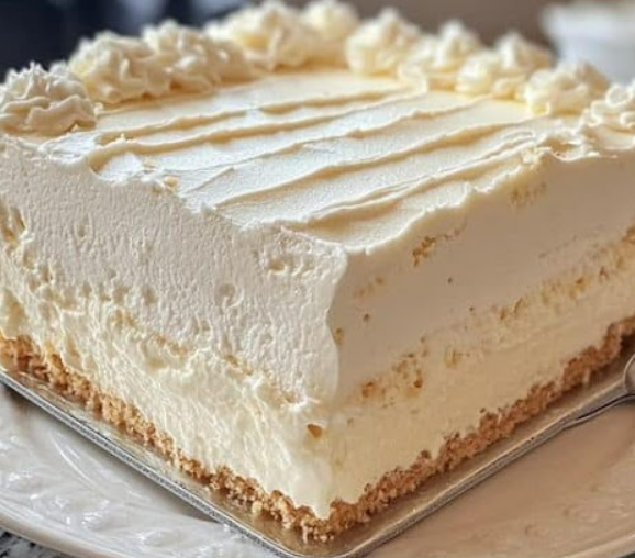 No-bake creamy vanilla cheesecake with a graham cracker crust, topped with whipped cream swirls