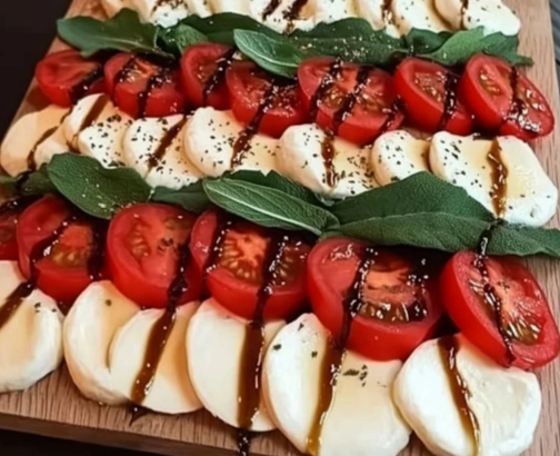 Caprese Salad Christmas Tree Recipe with tomatoes, mozzarella, and basil arranged on a wooden board.