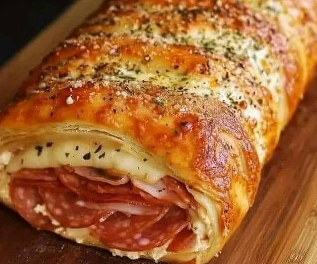 Stuffed Italian Stromboli Recipe with golden-brown crust, filled with layers of pepperoni, salami, and cheese on a wooden cutting board.