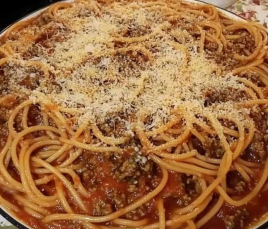 A skillet filled with homemade spaghetti and rich meat sauce, topped with herbs