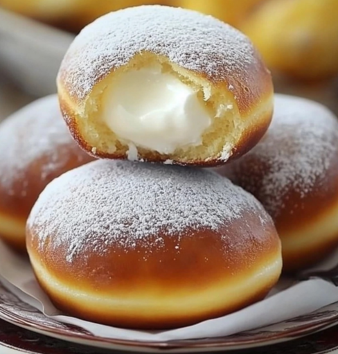 Golden brown Bomboloni dusted with powdered sugar, filled with creamy custard, served on a plate