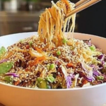 Crunchy Asian slaw with colorful shredded vegetables and sesame dressing being poured over the top.