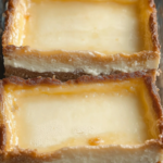 Creamy cheese bars in a glass baking dish with a golden crust and smooth, baked cheese filling.