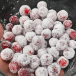 A glass bowl filled with sugared cranberries coated in sparkling white sugar.