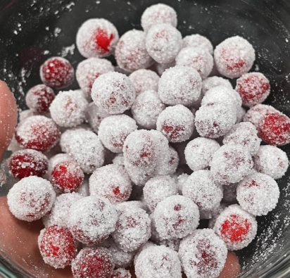 A glass bowl filled with sugared cranberries coated in sparkling white sugar.